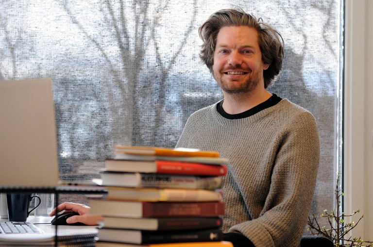 Anders Tviberg på kontoret bak en stabel bøker