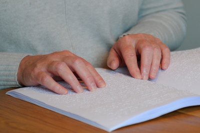 Nærbilde hender som leser punktskrift